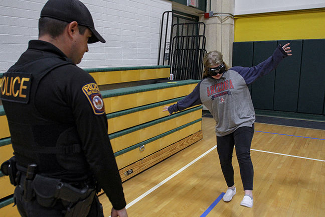  Teenage girl wearing drunk goggles tries to walk in a straight line as a police officer watches her